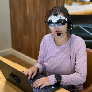 Dani wearing the VISORS prototype while typing on a laptop