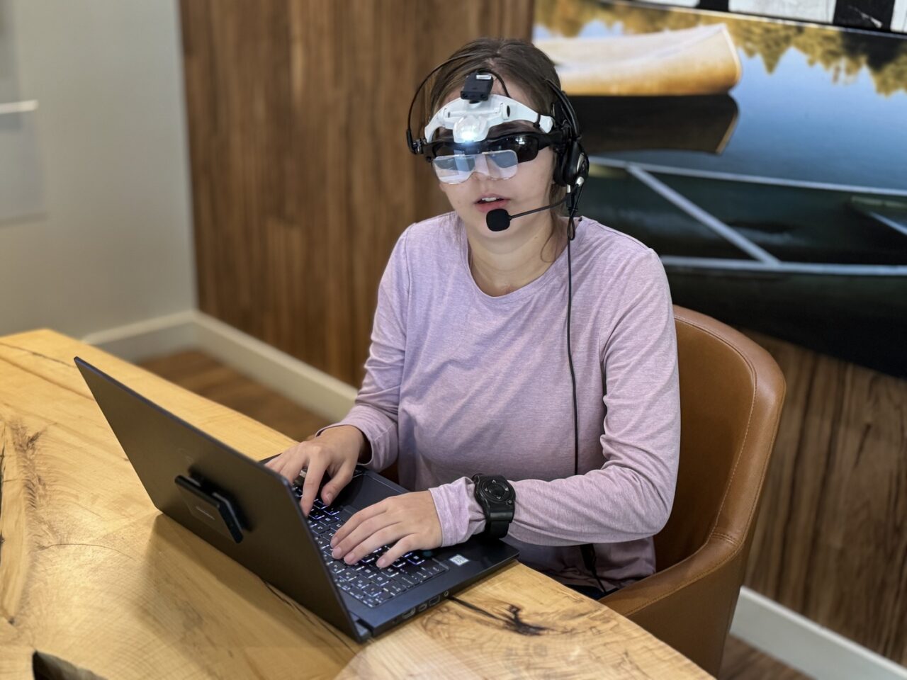 Dani wearing the VISORS prototype while typing on a laptop